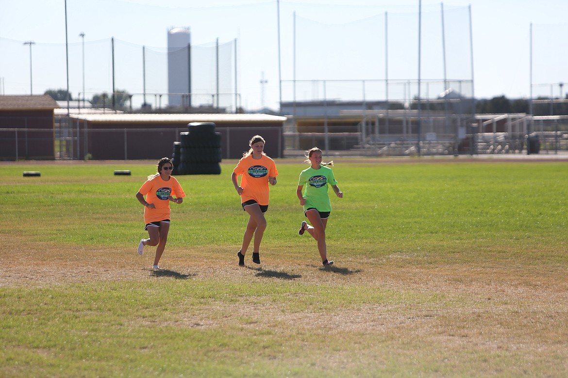 Moses Lake runners Natalie Bischoff, left, Jayden Nordstrom, center, and Janessa Phelps, right, finish workouts on a practice field at Moses Lake High School.