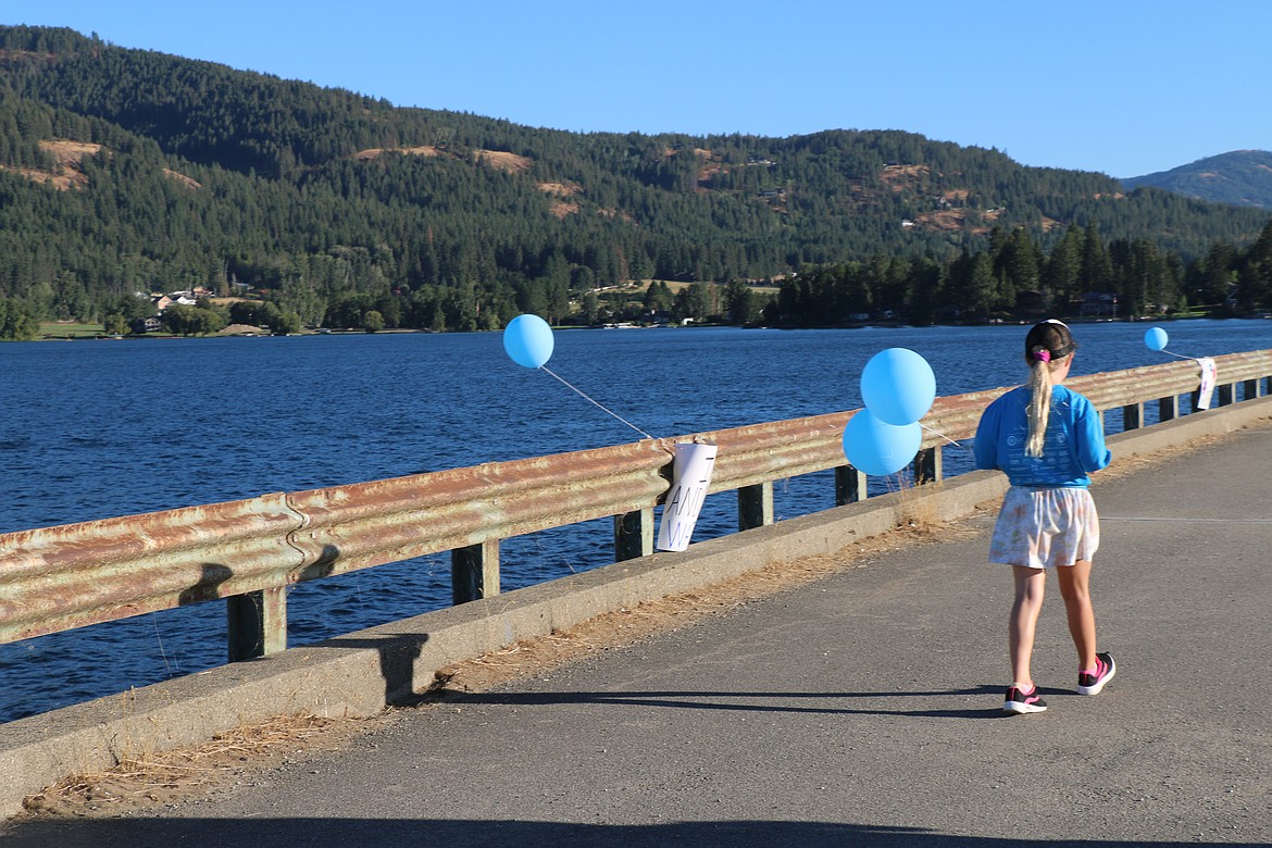 A youngster holds a balloon as she walks across the Long Bridge during Sunday's Walk for HOPE.