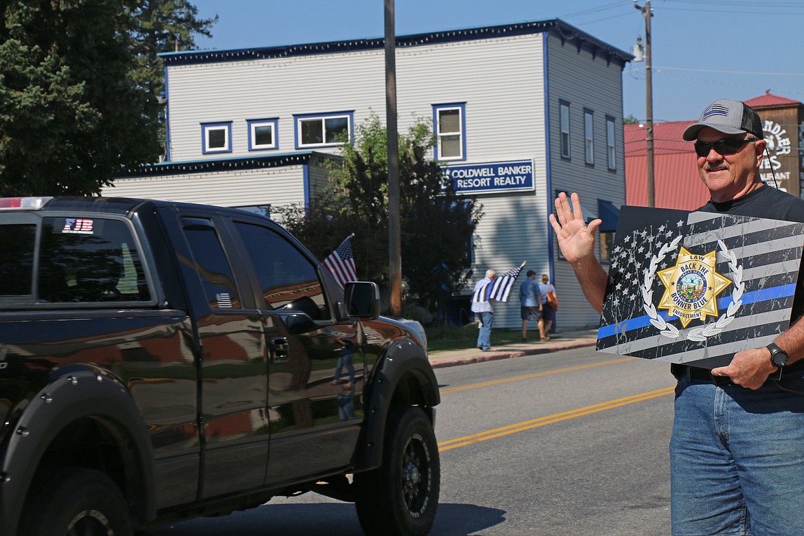 A man waves to a passing car as he takes part in the 2023 Back the Bonner Blue rally.