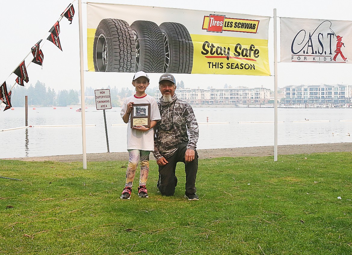 C.A.S.T. for Kids participant Haylee Madison, 9, smiles for the camera with Mark Tubbs, boat captain, after receiving a plaque Sunday.