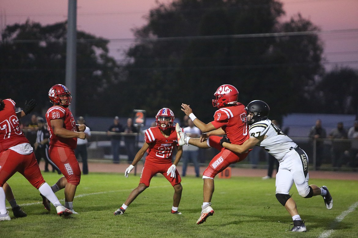 Othello quarterback Maddox Martinez (7) passes the ball while being wrapped up by a Royal defender.