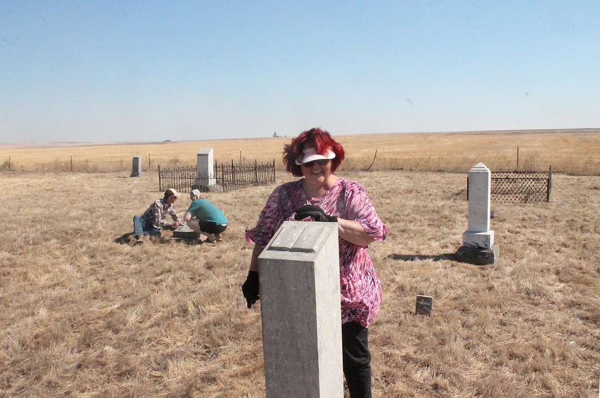 Judy Evans Lindhag cleans up a headstone at the Welsh Cemetery Saturday morning. Behind her, Aren Orsen, left, and Liz Orsen carefully remove buildup from a headstone. The Orsens work in historic preservation, they said, so they know a bit about old cemeteries. They were the ones who brought the cemetery’s existence to the attention of the Puget Sound Welsh Association.