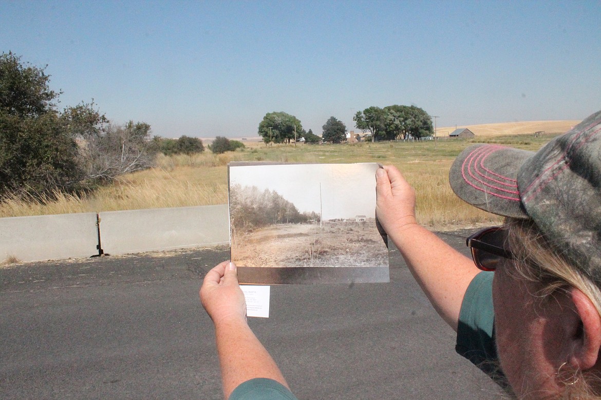 Cindy Williams Rohde holds up a photo of Williams Grove that was taken when the Welsh settlers would hold their annual picnic there, in front of the site as it appears today.