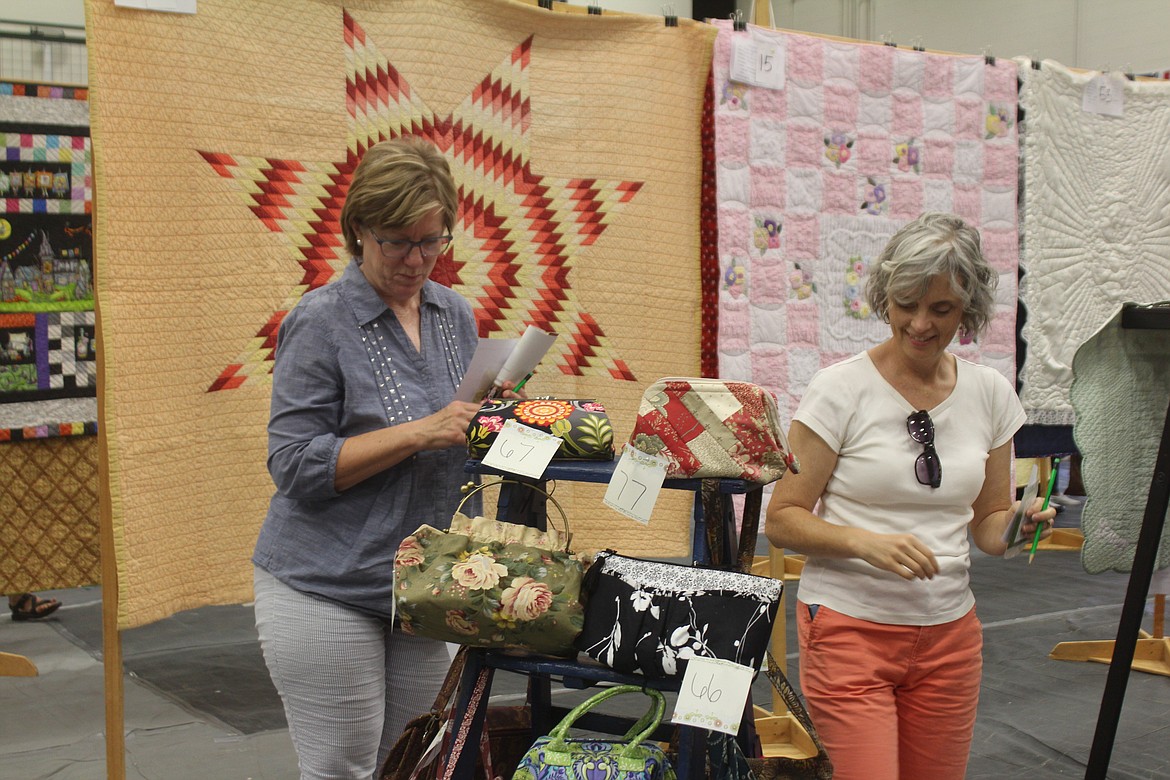 Jeanie Hyer, left, and Debbie Oda, right, evaluate the entries in the Farmer Consumer Awareness Day quilt show.