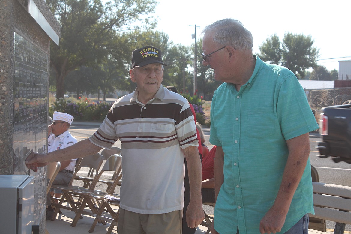 Mark VanBuskirk (left) points out the name of a fellow veteran to neighbor Bill Morris (right) during Saturday’s ceremony at the Veterans Recognition Wall in Quincy.