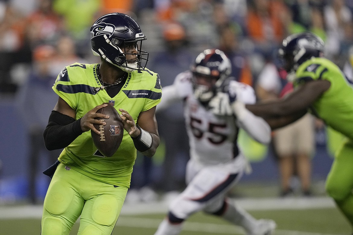 Seattle Seahawks quarterback Geno Smith, left, drops to pass against the Denver Broncos during the second half of an NFL football game, Monday, Sept. 12, 2022, in Seattle. The Seahawks won 17-16.