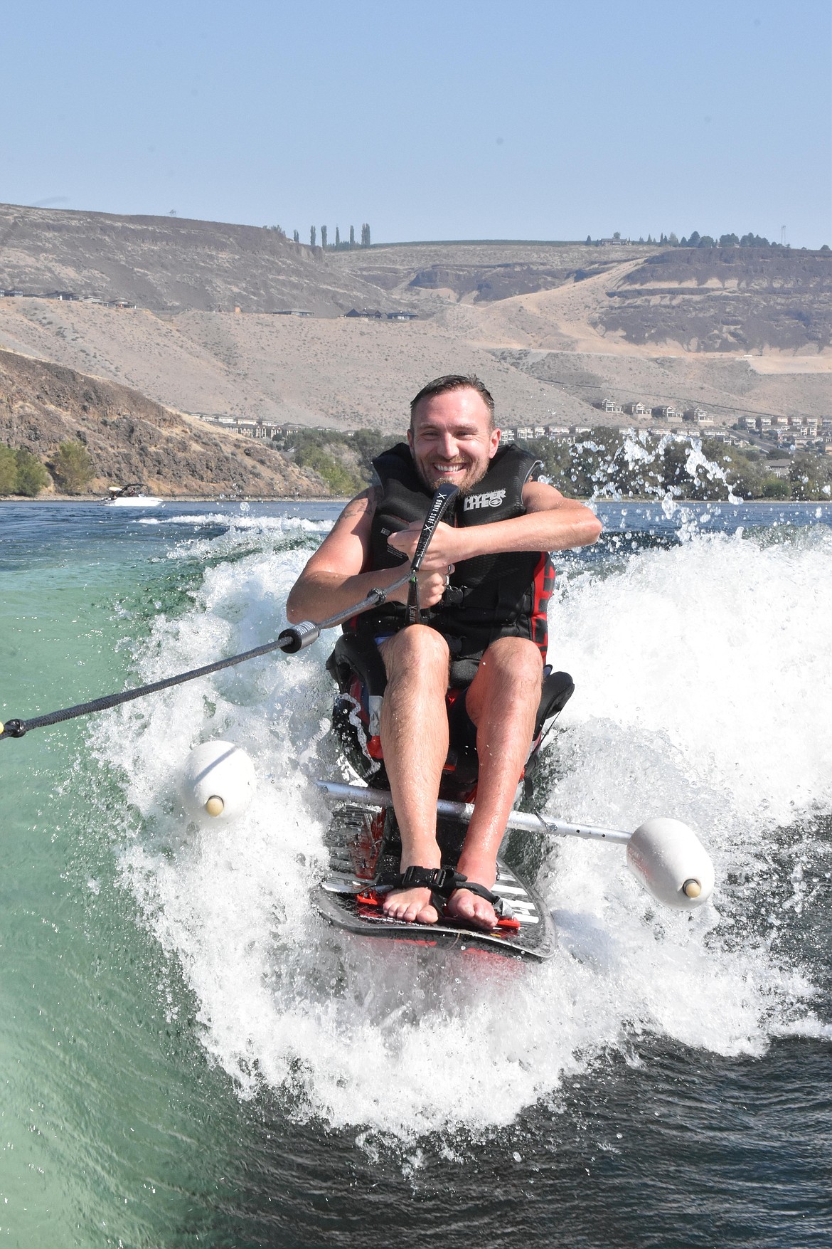 Patrick Edlin smiles as he wakesurfs on a sit-down board on the Columbia River Saturday.