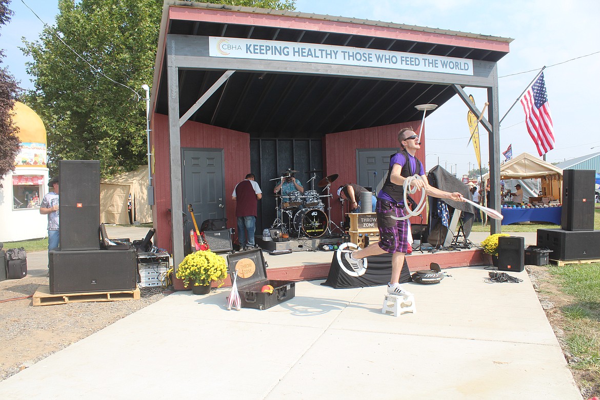 Juggler Jeremiah Johnston spins and juggles on the new concrete pad in front of the new stage at the Othello Fairgrounds, while the band Southbound sets up in the background. The stage was built with volunteer labor and help from local businesses.