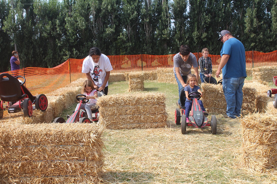 Volunteers Gabriel Alfaro (left) and Julio Gomez (right) help racers Kamryn Gardner (left) and Monroe Loera (right) around the new obstacle course track in the Kid Zone at the Othello Fairgrounds. Volunteers put in time over the summer making improvements to the grounds.