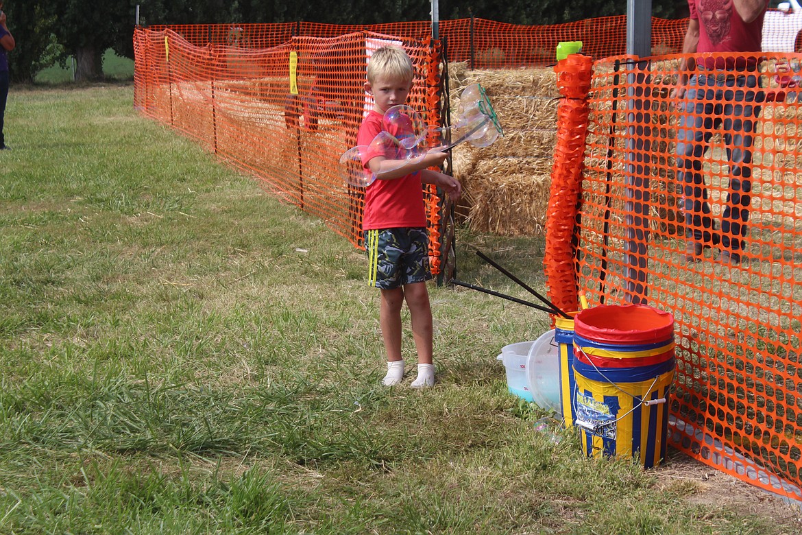 A fairgoer plays with bubbles at the Kid Zone, the expanded area for children’s games at the Othello Fairgrounds.