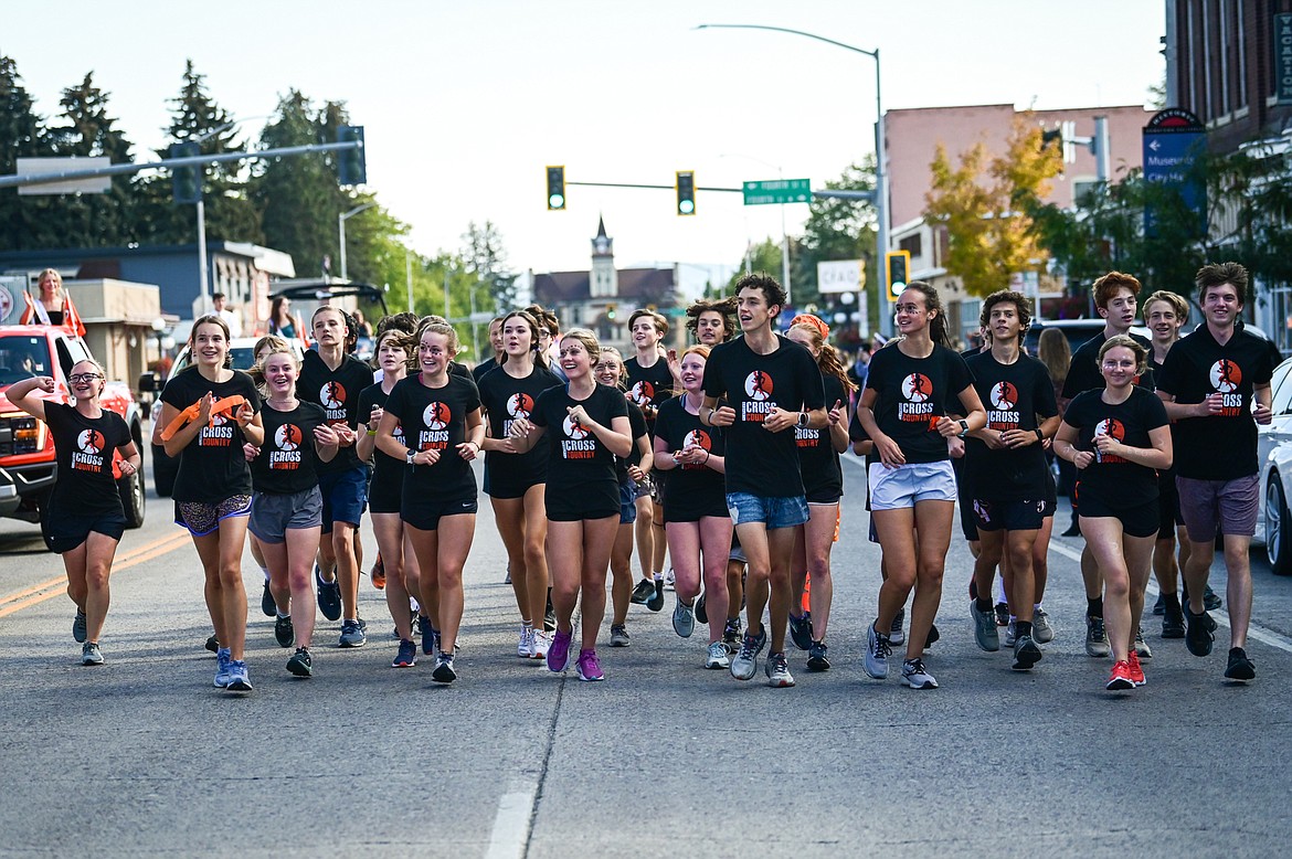 The cross country team runs alongside the procession during the Flathead High School Homecoming Parade along Main Street on Wednesday, Sept. 21. (Casey Kreider/Daily Inter Lake)