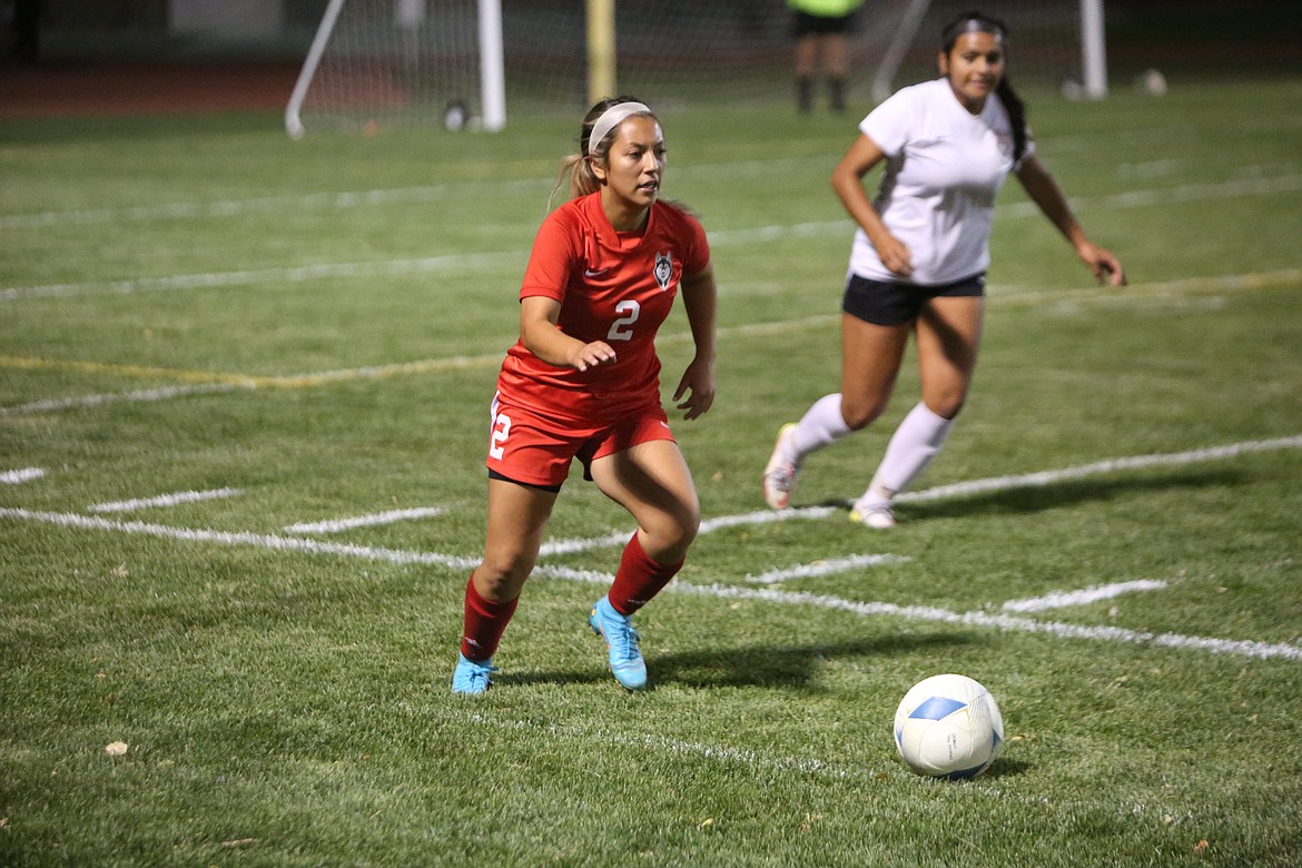 Othello senior Carla Gonzalez looks to pass the ball to a teammate while near the sideline.