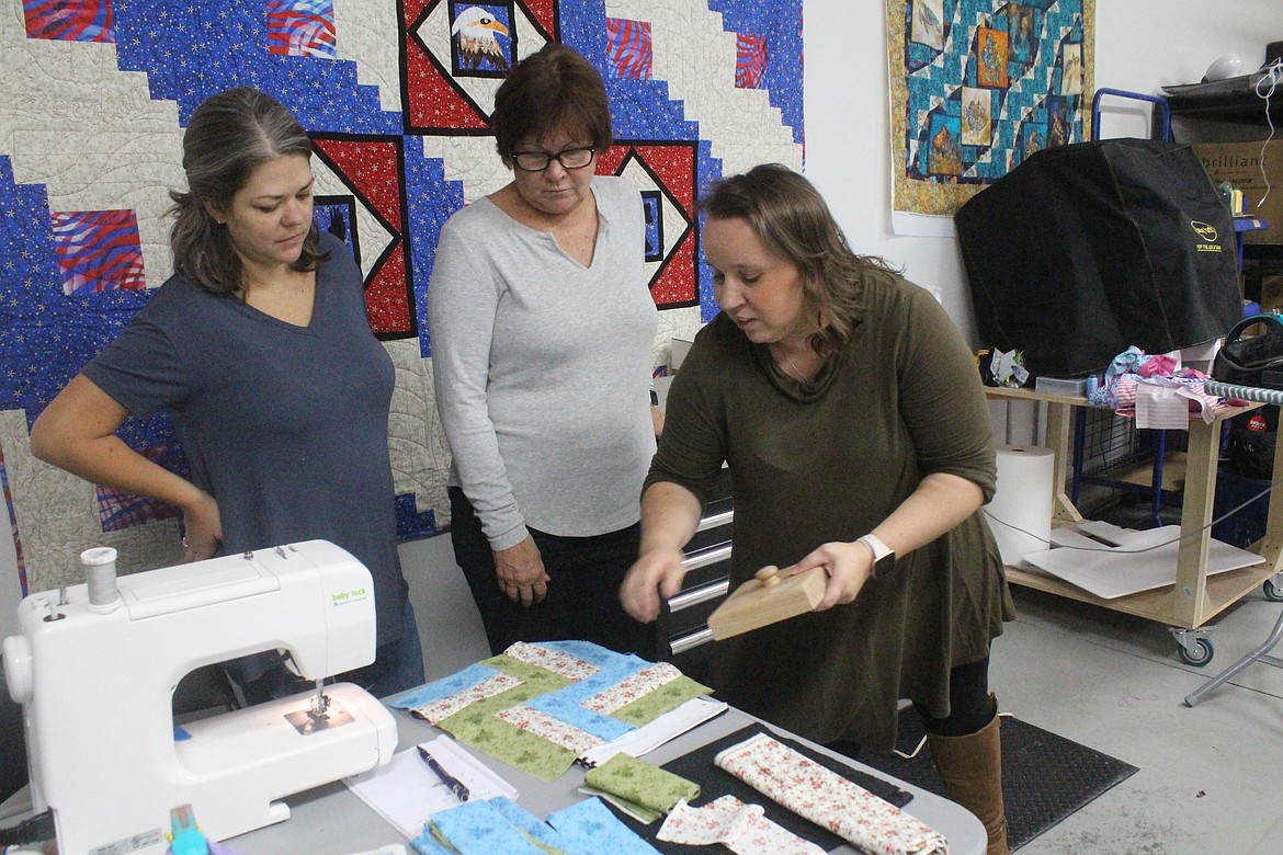 Owner Sophie Mattson (right) demonstrates a technique for students Jade Whittle (left) and Nancy Whittle (center) during a class at Stitch N Time, Mattson’s Moses Lake shop.