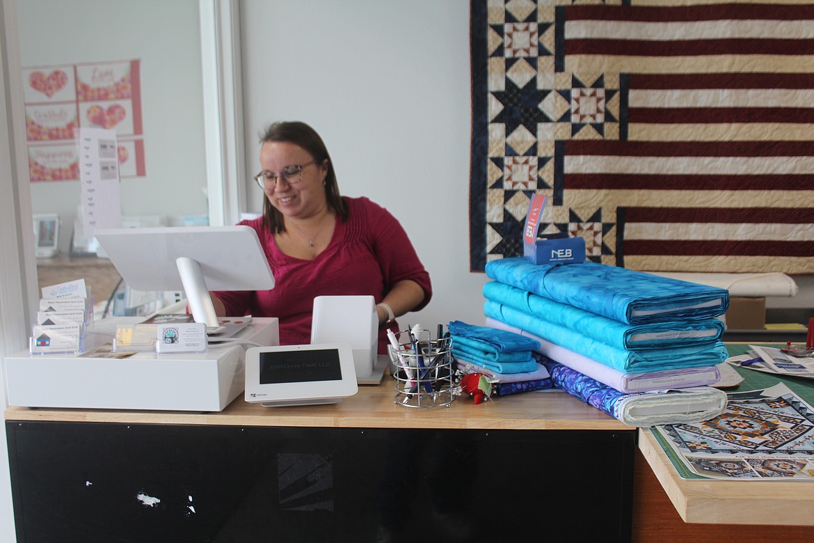 Surrounded by fabric, Stitch N Time owner Sophie Mattson rings up a sale.