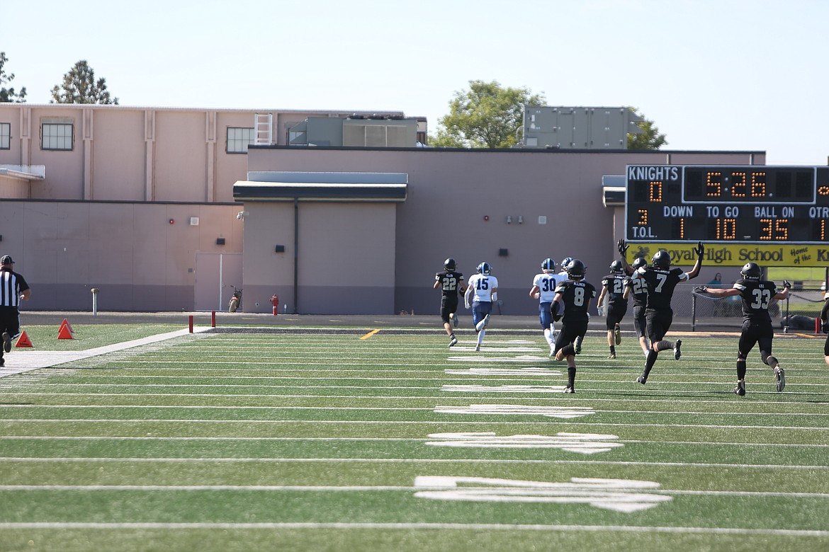 Royal’s Ethan Ellis (22) runs back a kickoff for a touchdown while teammates celebrate.