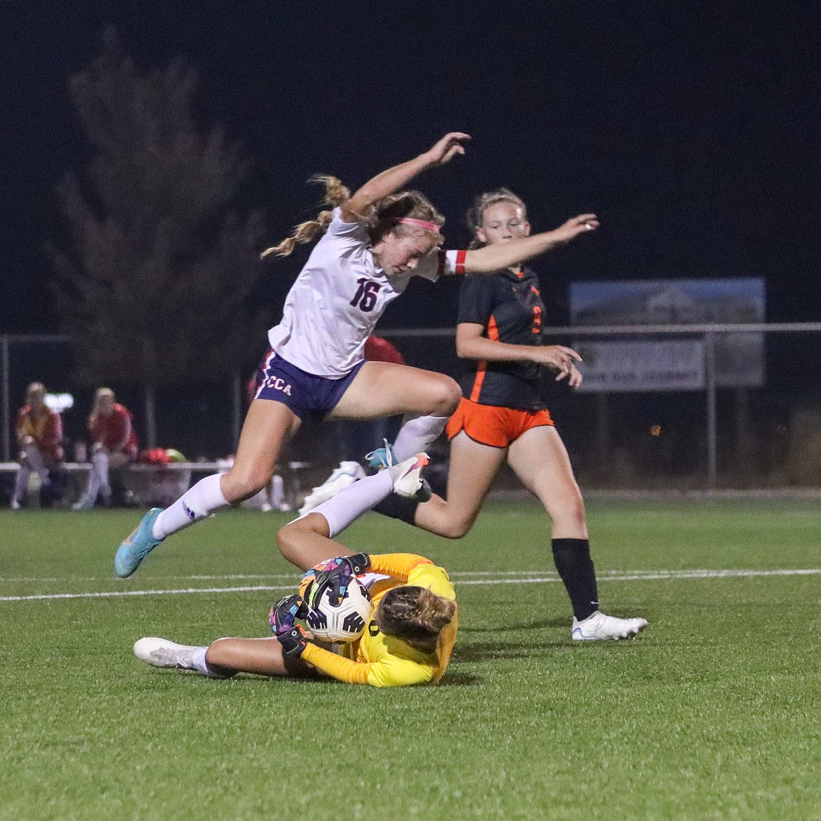 Photo by JERRY VICK
Rebekah Hines (16) of Coeur d'Alene Charter Academy leaps over Post Falls goalkeeper Rose McGowan on Saturday night at The Fields at Real Life Ministries in Post Falls.