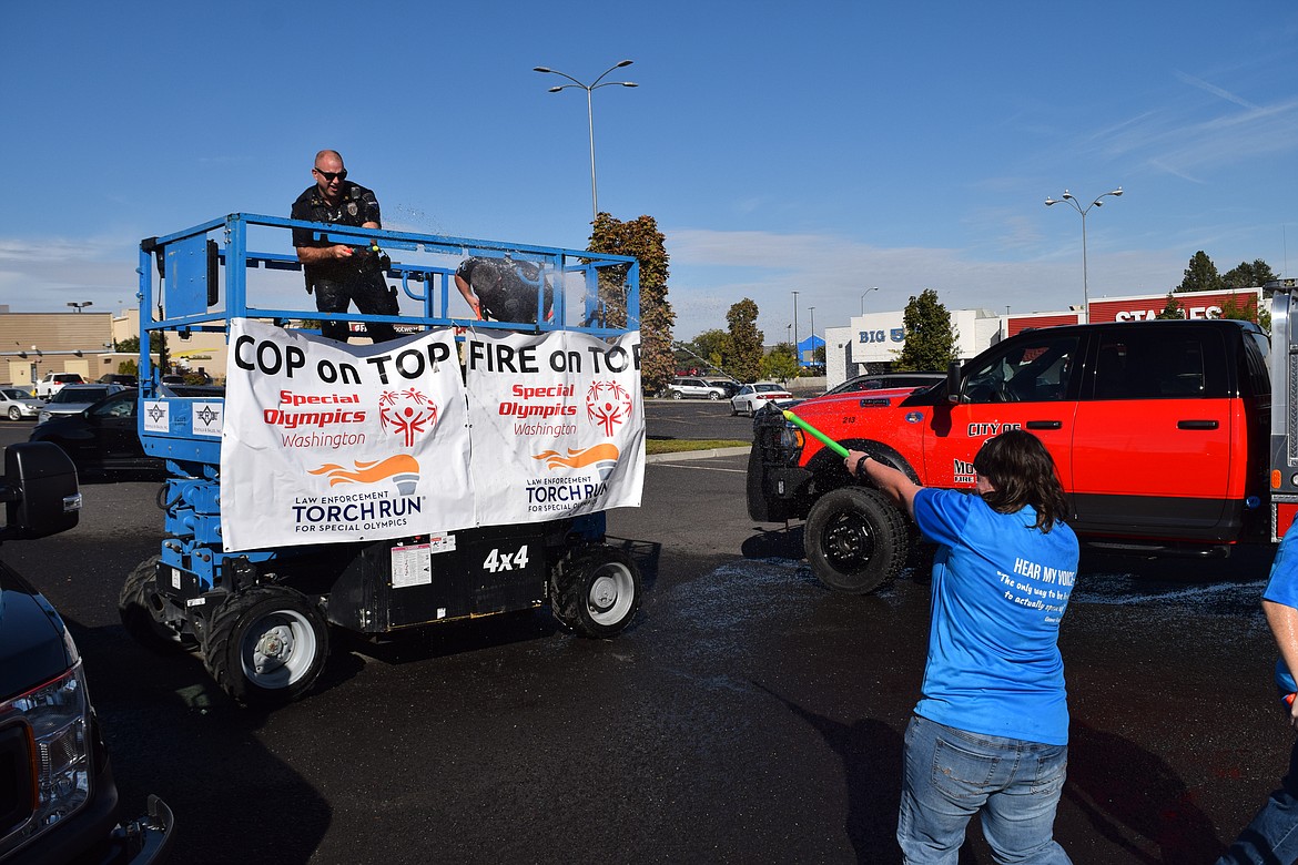 Special Olympics athlete Becky Jones “open fire” with a water cannon on Moses Lake Police Department Capt. Mike Williams during a fundraiser for Special Olympics Washington in Moses Lake on Friday.