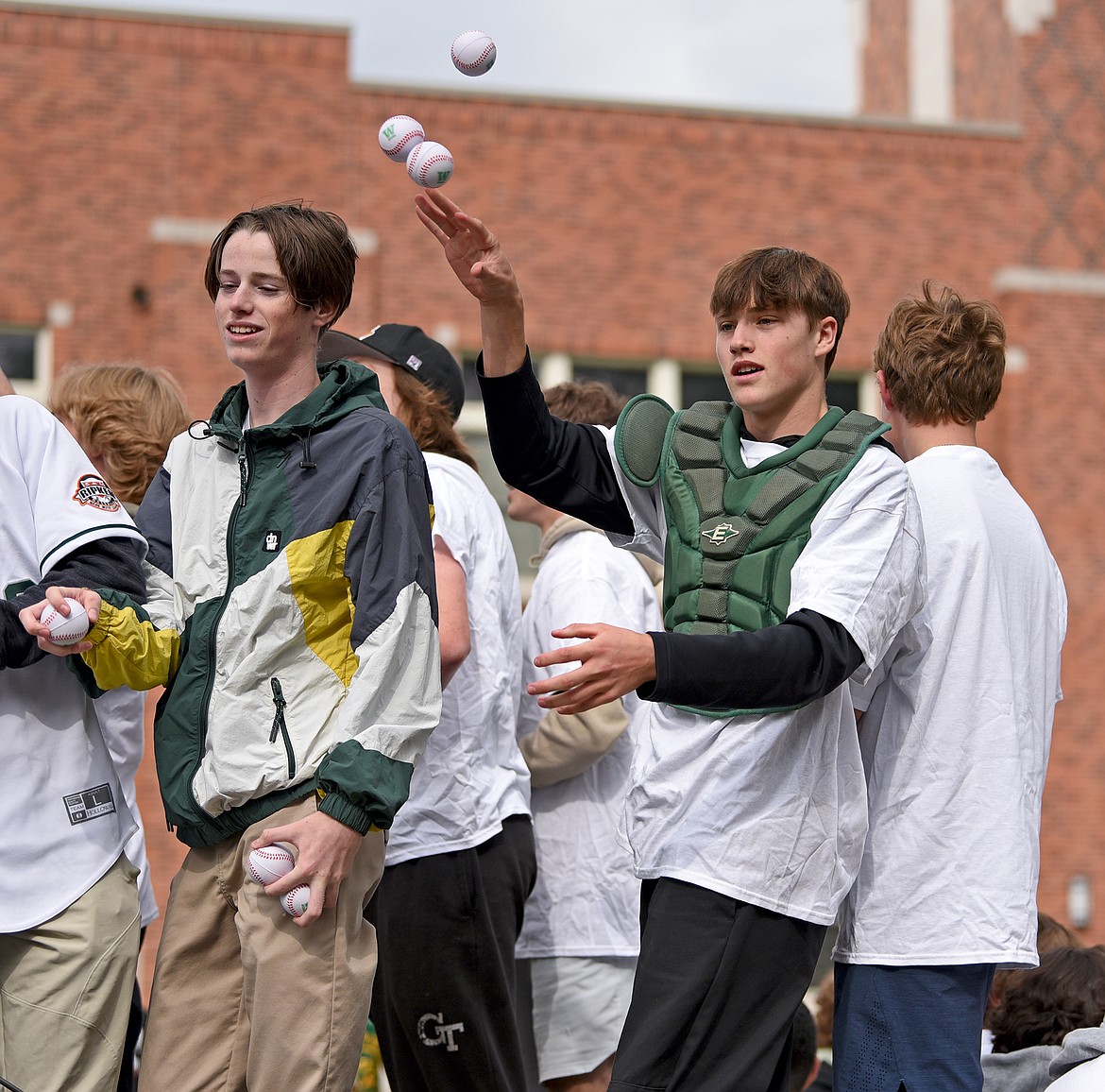 Members of the brand new Whitefish Baseball team throw play baseballs to kids lined up along Second Street in the 2022 Whitefish Homecoming Parade on Friday. (Whitney England/Whitefish Pilot)