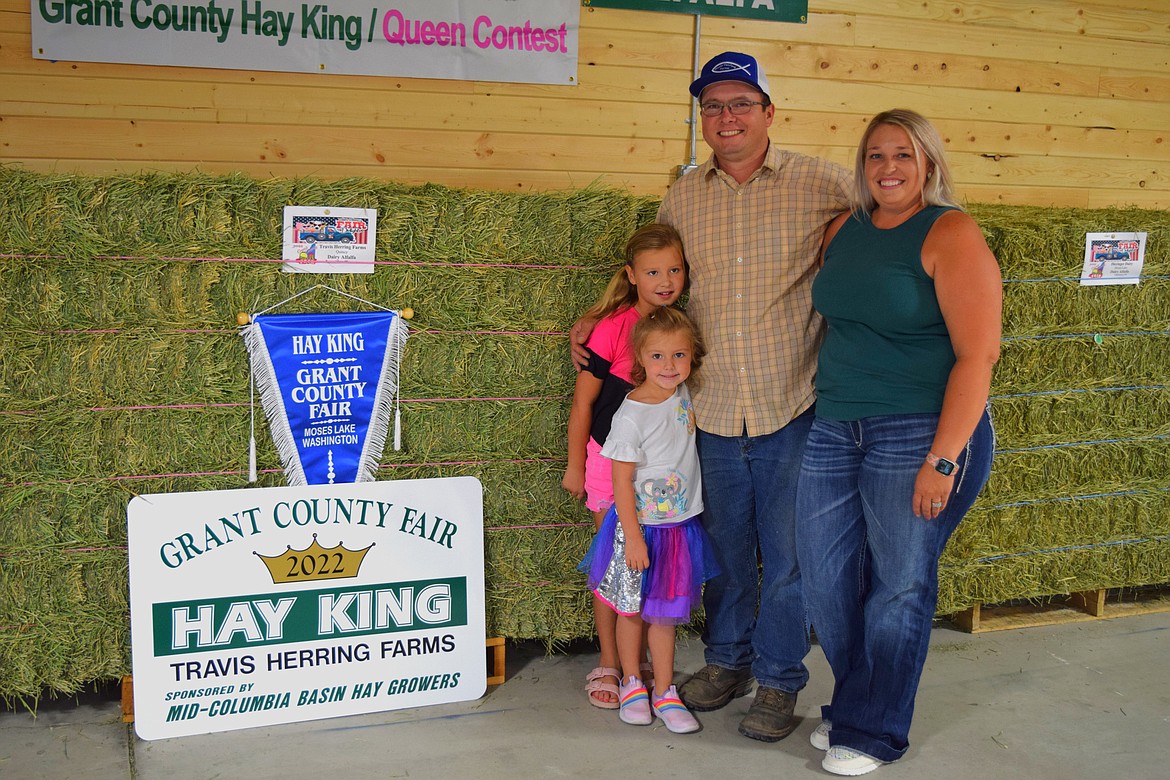 Travis Herring and his wife Jennifer and their two children, Cheyenne and MacKenzie, in front of a bale of their award-winning hay. Herring was named Hay King at this year’s Grant County Fair.