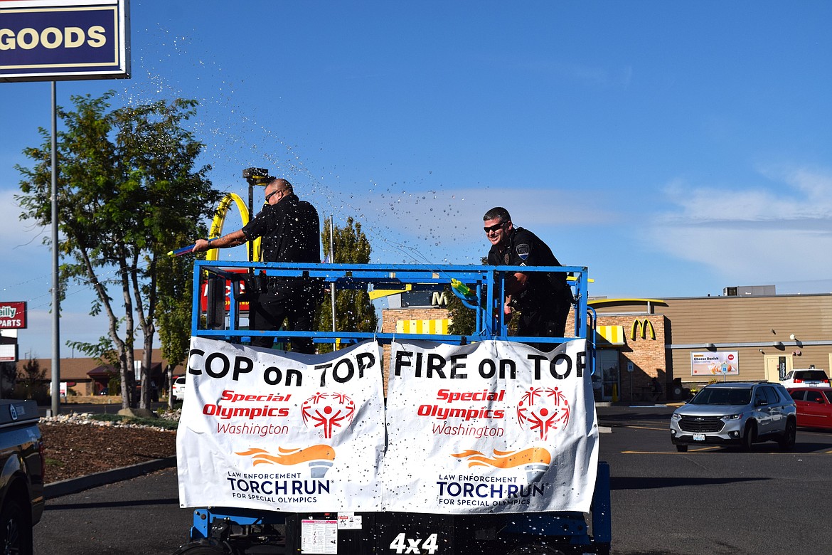 Moses Lake Police Department Capt. Mike Williams (left) and Sgt. Jeff Sursely (right) fend off an “attack” from Special Olympics athletes trying to sneak up on them during the “Fire & Cop On Top” fundraiser in Moses Lake on Friday in which first responders volunteer to get soaked — and soak back — to raise money for Special Olympics Washington.