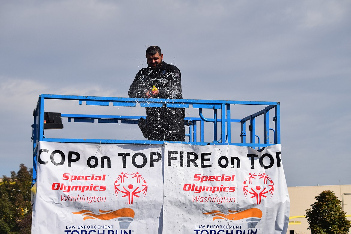 Othello Police Department officer Tyson Cox lets loose with three water cannons in an attempt to fend off an “attack” during the “Fire & Cop on Top” fundraiser in Moses Lake on Friday.