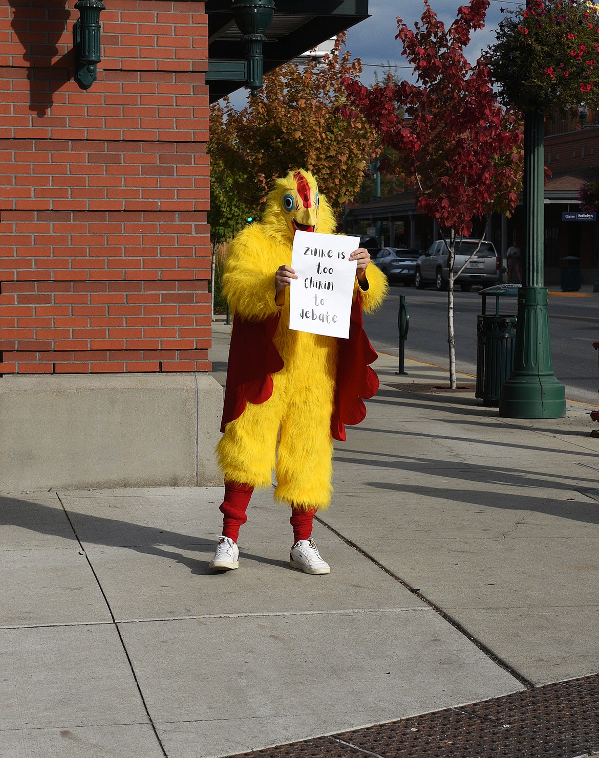 Someone in a chicken suit holding a sign saying, "Zinke is too chikin to debate" greeted the public as they arrived at City Hall for the debate Friday night. (Julie Engler/Whitefish Pilot)