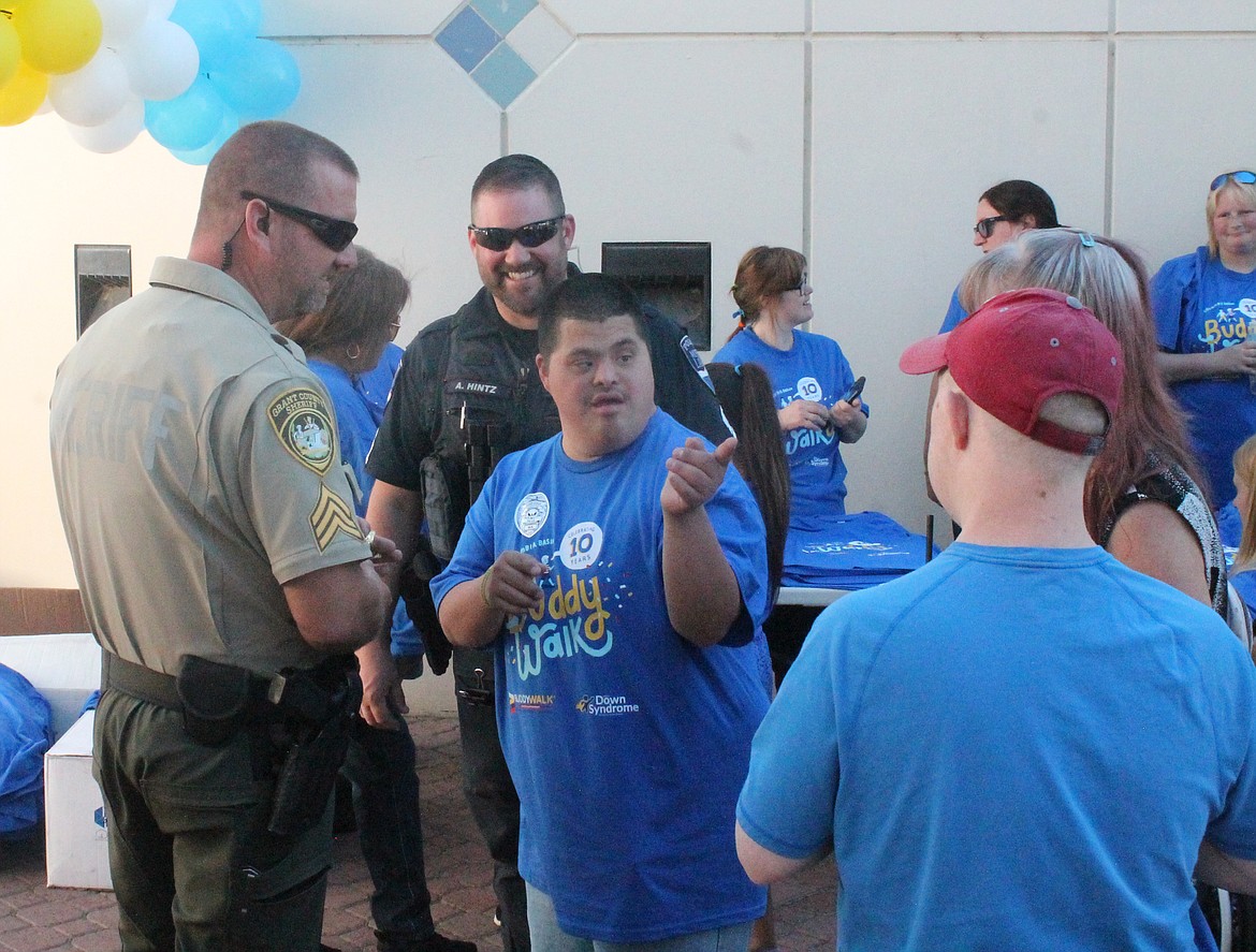 A Grant County Sheriff’s Deputy and a Moses Lake Police officer talk with some participants at the Buddy Walk Saturday. This was the first time the first responders have been a part of the event, held annually for people with Down syndrome and their families.