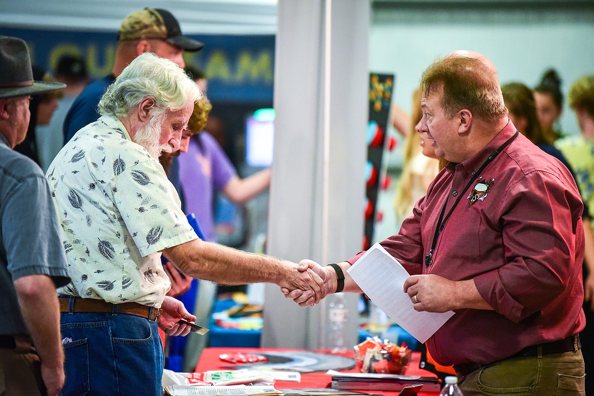 Eddie Wise, right, Operations Manager with Integrated Security Solutions in Kalispell, shakes hands with an attendee after giving him a business card at the 2022 Job & Veteran Opportunity Fair at the Flathead County Fairgrounds Expo Building on Wednesday, Sept. 28. (Casey Kreider/Daily Inter Lake)