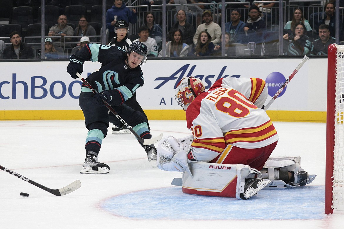 Seattle Kraken center Jared McCann, left, passes the puck to Jaden Schwartz as Calgary Flames goalie Dan Vladar defends during the second period of a preseason NHL hockey game Tuesday, Sept. 27, 2022, in Seattle.