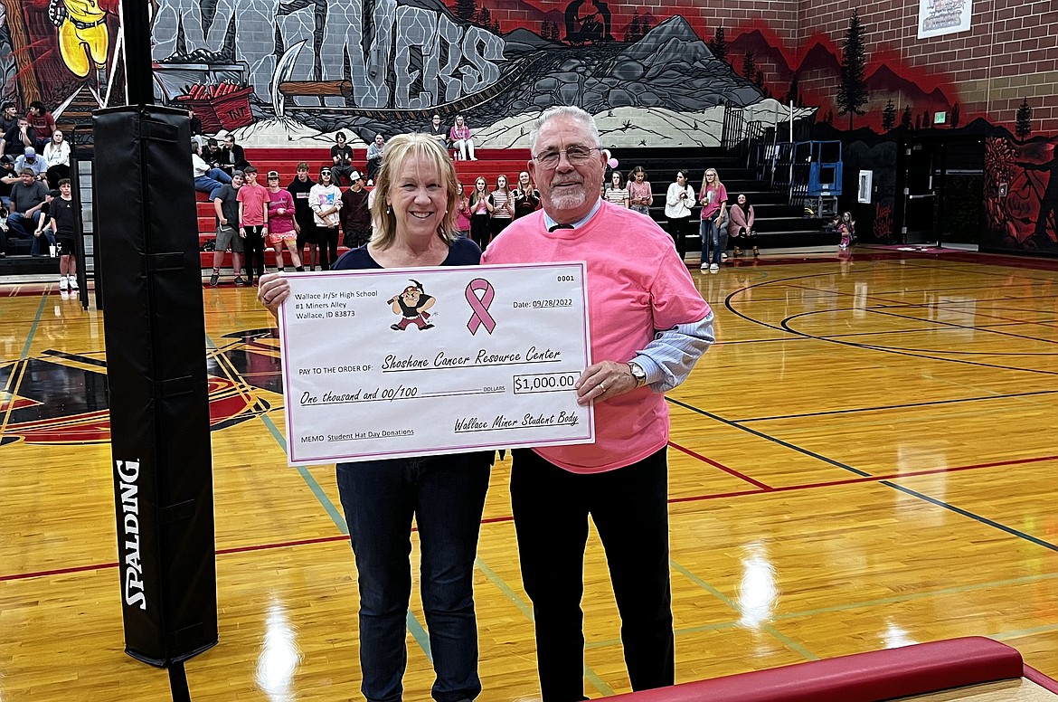 Wallace Jr./Sr. High School Principal Don Almquist presents a check for $1,000 to Carol Reager with the Shoshone Cancer Resource Center during a break in the action at Dig Pink Night.