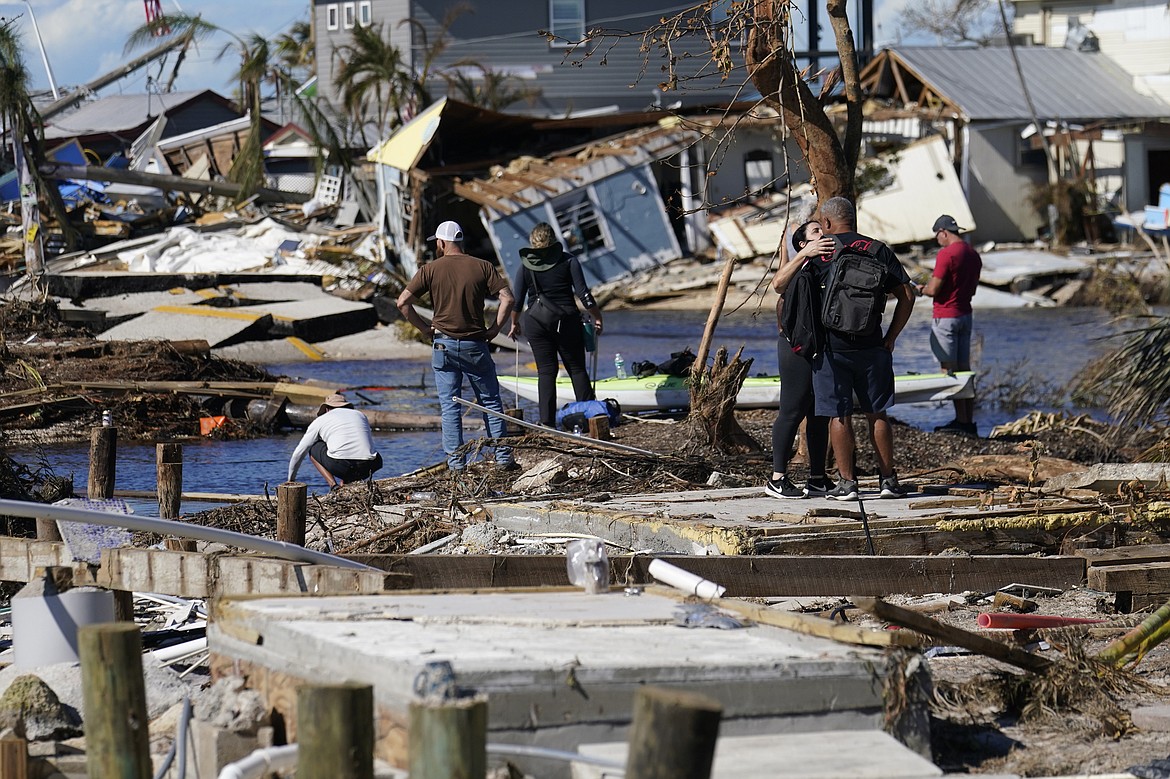 People stand on the destroyed bridge to Pine Island as they view the damage in the aftermath of Hurricane Ian in Matlacha, Fla., Sunday, Oct. 2, 2022. The only bridge to the island is heavily damaged so it can only be reached by boat or air. (AP Photo/Gerald Herbert)