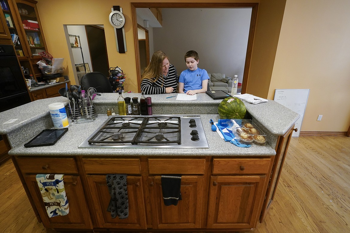 Lisa Manwell works on school work with her son John Jinks, 12, at their home in Canton, Mich., Wednesday, Sept. 21, 2022. Manwell says her son was improperly removed from his classroom last year because of behaviors that stemmed from his disability. (AP Photo/Paul Sancya)