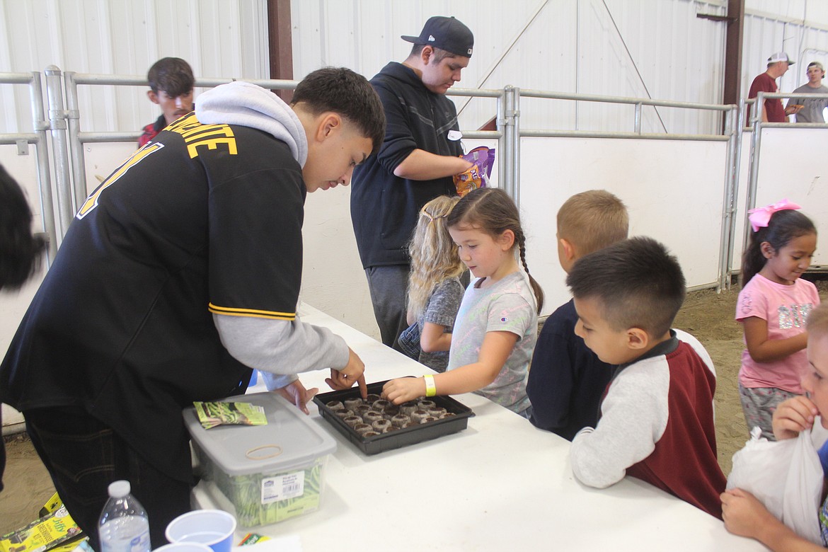 Isaiah Gonzalez (left) shows a first-grader how to plant a seed during First Grade Farm Day at the Grant County Fairgrounds Tuesday.