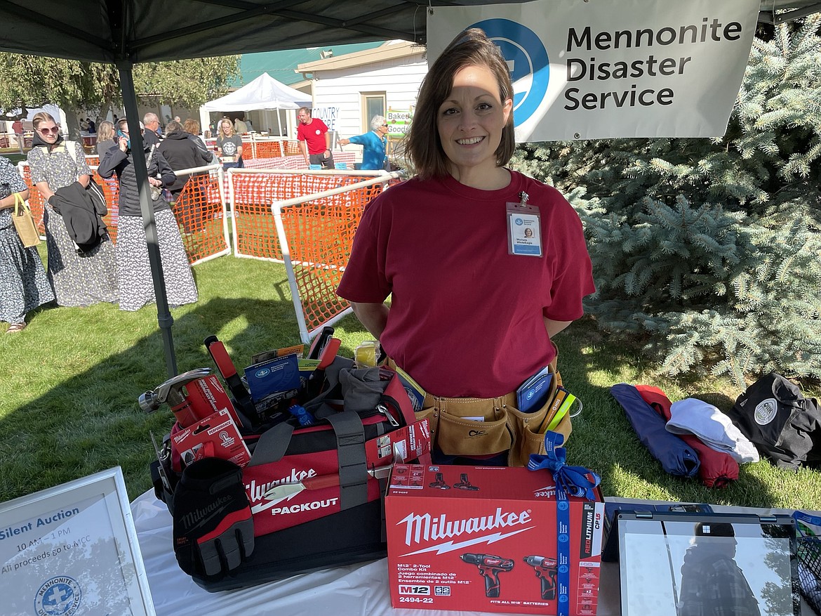 Michele WhiteEagle, regional chair of Mennonite Disaster Service, stands in her information booth at the Mennonite Country Auction on Saturday near Ritzville, with the tools she plans to auction off to help raise money for the church’s national and global relief efforts.