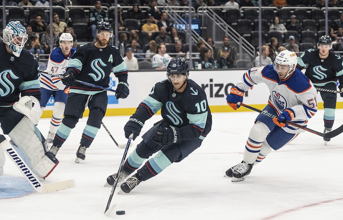 Seattle Kraken forward Matty Beniers, center, skates against Edmonton Oilers forward Luke Esposito during the second period of a preseason NHL hockey game Sept. 26 in Seattle.