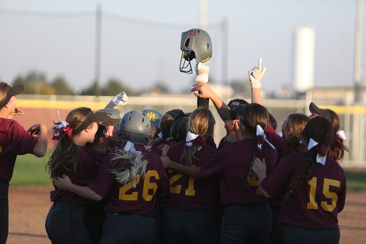 The Moses Lake Maverick slowpitch team gathers around senior Katelyn Kriete after she hits a walk-off single for a 15-14 win.