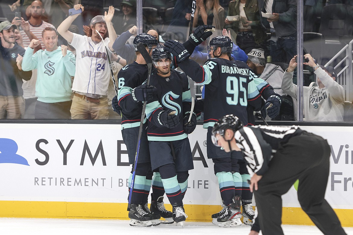 Seattle Kraken forward Matty Beniers, second from left, is congratulated by Adam Larsson (6) and Andre Burakovsky after scoring a goal against the Vancouver Canucks during the second period of a preseason NHL hockey game Oct. 1 in Seattle.