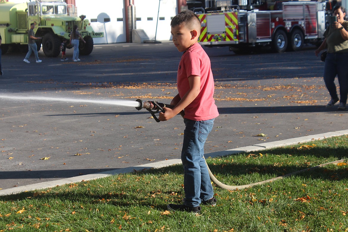 Sean Pio tries out the fire hose during the Grant County Fire District 3 open house.