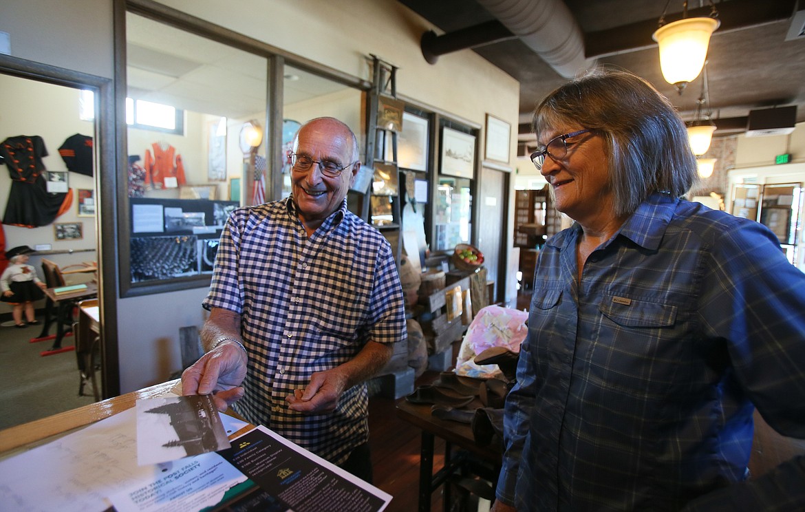 Marv Patzer and Post Falls Historical Society President Kim Brown on Thursday look at a postcard with a 1923 photo of the then-new Chapin Building, which is now home to the Post Falls Museum. The society is seeking community stories about the building.