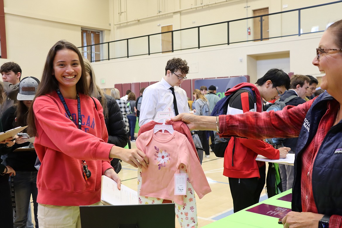 A Lake Pend Oreille School District senior is presented with baby clothes after learning she was assigned children at this week's "My Life, My Money" finance fair.
