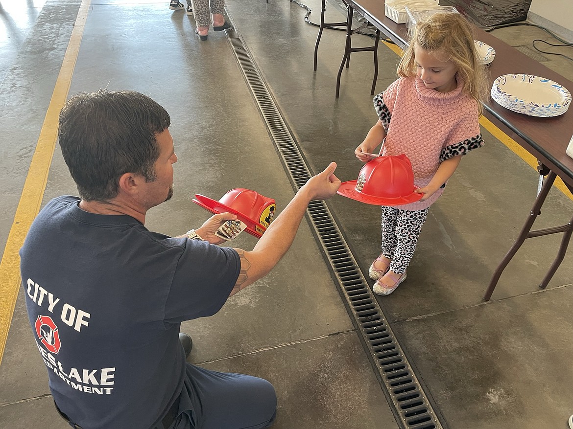 Moses Lake Firefighter Schrade Rouse hands Mabel Hickok, 4, a fire hat and a sticker during the annual Pancake Breakfast jointly organized by the Moses Lake Lions Club and Local 1258 of the International Association of Fire Fighters. Proceeds from the breakfast, which was started a number of years ago to coincide with the official opening of hunting season, will go to help the Lions Club provide the needy with eyeglasses and hearing aids and to the union’s benevolent fund to help kids get warm clothes for the winter.