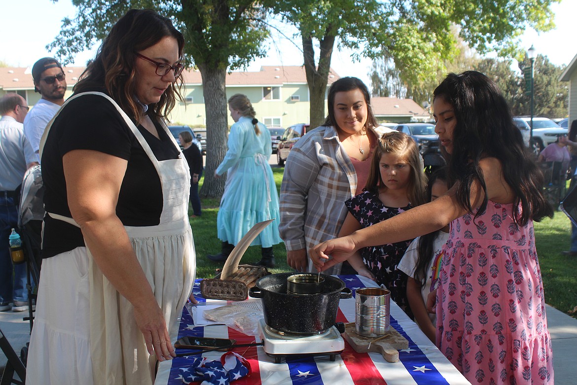 Camila Martinez dips a candle wick, while volunteer Joey Hodges keeps an eye on the wax, during the “Celebration of Cultures,” part of the Hometown Harvest Fest in Quincy Saturday.