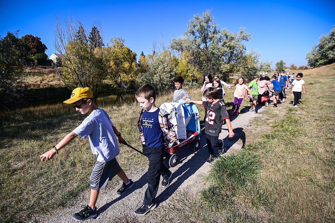 Hedges Elementary School third-grade students pull their wagons during a lesson on the Oregon Trail at Dry Bridge Park in Kalispell on Tuesday, Oct. 18. (Casey Kreider/Daily Inter Lake)
