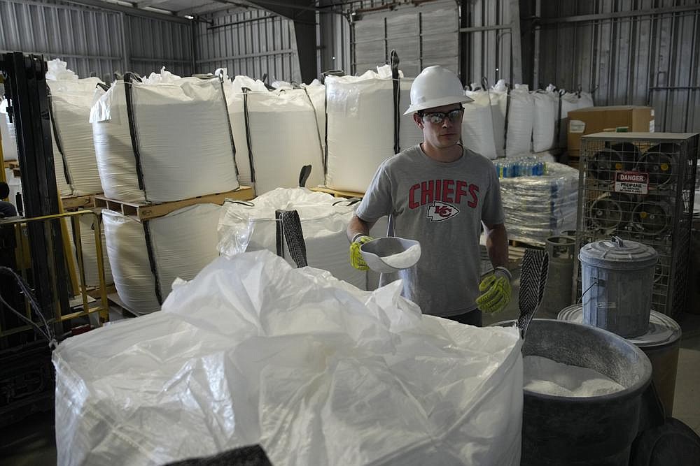 Tyler Kirkland adds a scoop to a large bag of lithium carbonate at Albemarle Corp.'s Silver Peak lithium facility, Thursday, Oct. 6, 2022, in Silver Peak, Nev. The Biden administration on Wednesday, Oct. 19, awarded $2.8 billion in grants to build and expand domestic manufacturing of batteries for electric vehicles in 12 states. A total of 20 companies, including Albemarle Corp., will receive grants for projects to extract and process lithium, graphite and other battery materials, manufacture components and strengthen U.S. supply of critical minerals, officials said.