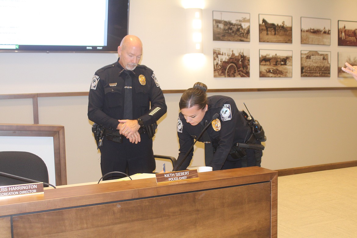 New Quincy Police Department officer Emily Pratt, right, signs her oath of office Tuesday as QPD Chief Keith Siebert looks on.