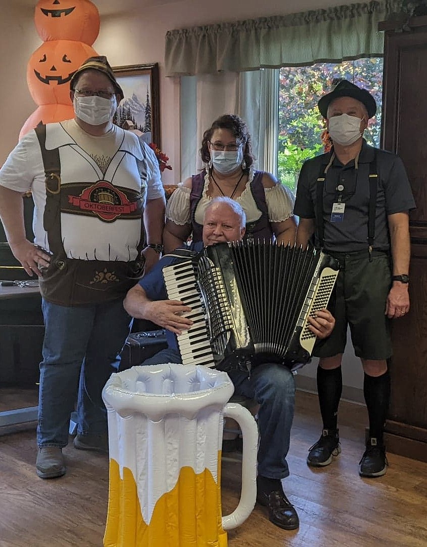 Silver Wood Village Administrator Ken Mitchell, CNA Carla Wickam and Recreational Director David Zumstein celebrate Oktoberfest with accordion player Anton Lazorovl and residents.