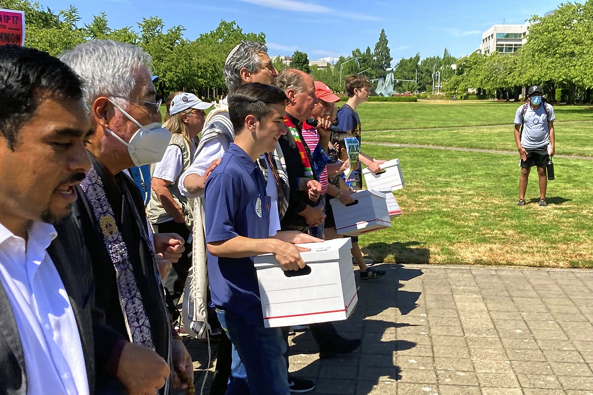 Backers of a proposed initiative that would require individuals to secure permits to buy firearms and ban large-capacity magazines deliver the signatures of thousands of voters on July 8, 2022, to state election offices in Salem, Ore. (AP Photo/Andrew Selsky, file)