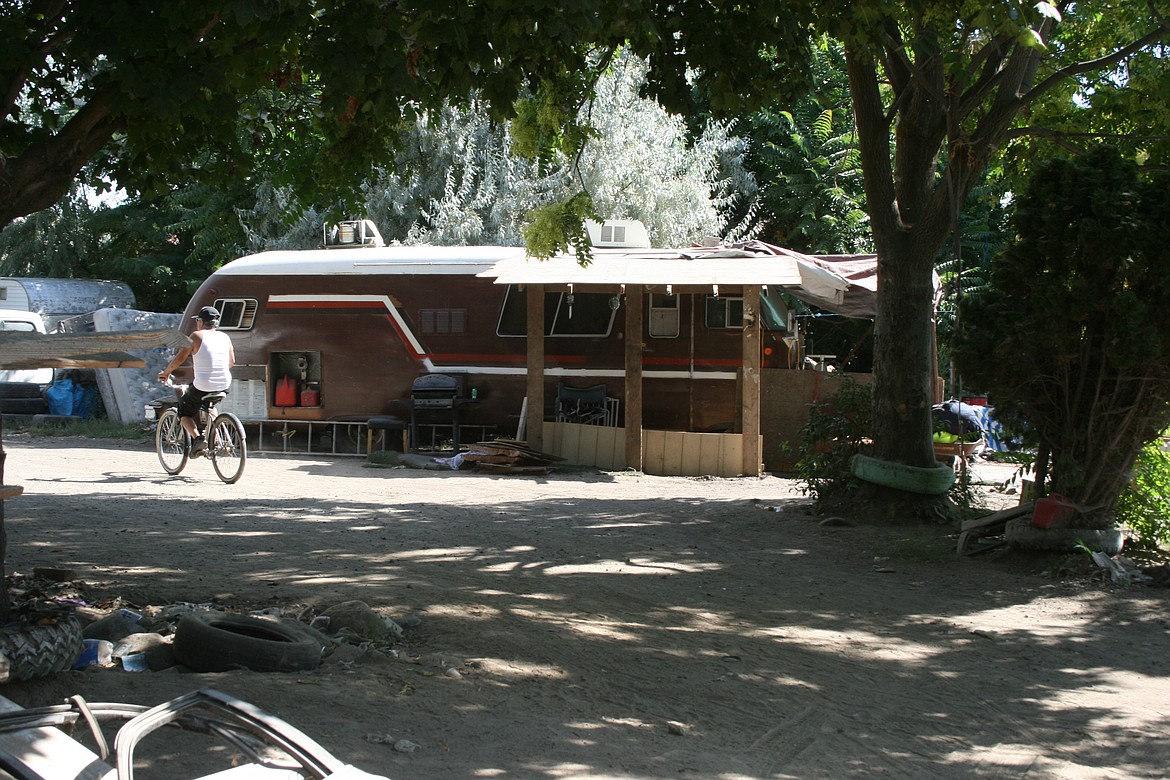 A resident rides by one of the non-operational motorhomes in an encampment near Othello.