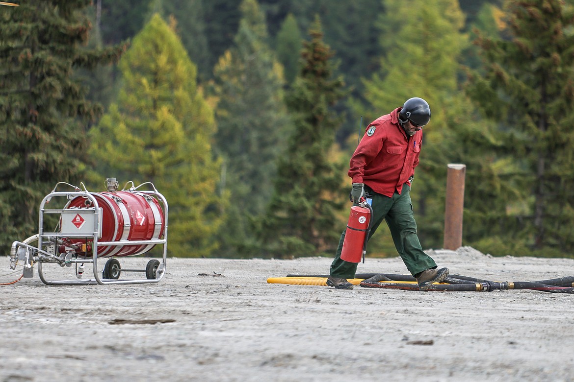 A Forest Service airman holds a can of fire extinguisher while the helicopter is loaded with Flash 21 at Big Mountain on Oct. 20. (JP Edge photo)