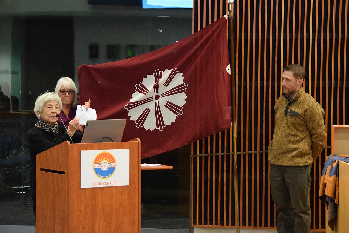 Moses Lake-Yonezawa Sister City Committee member Ginny Hirai explains the meaning of the Yonezawa, Japan, city flag (held up by fellow committee member Terry Moore) during a regular session of the Moses Lake City Council on Tuesday while Council Member Dustin Swartz, who was an exchange student to Yonezawa, looks on.